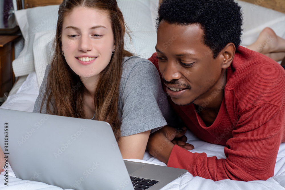 Fototapeta premium Young couple using laptop in a bed at home.