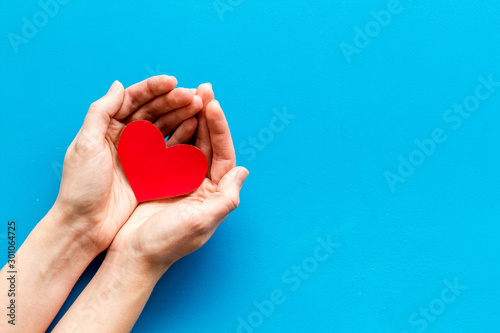 Heart icon. Paper heart in hands on blue background top view space for text