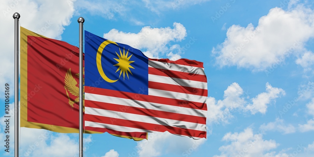 Montenegro and Malaysia flag waving in the wind against white cloudy blue sky together. Diplomacy concept, international relations.