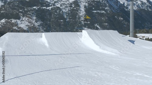 Snowboarder in Snowpark with Moving Chair Lift on Sunny Weather Day 5