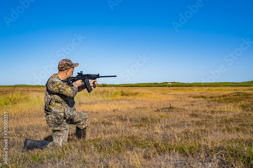 man with a gun standing in the field