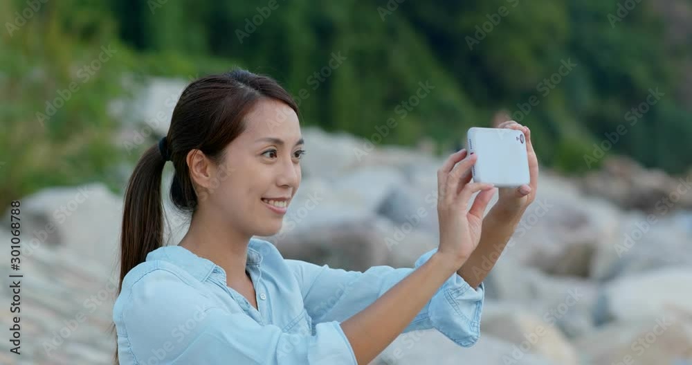 Woman take photo on cellphone at seaside Woman take photo on cellphone at seaside