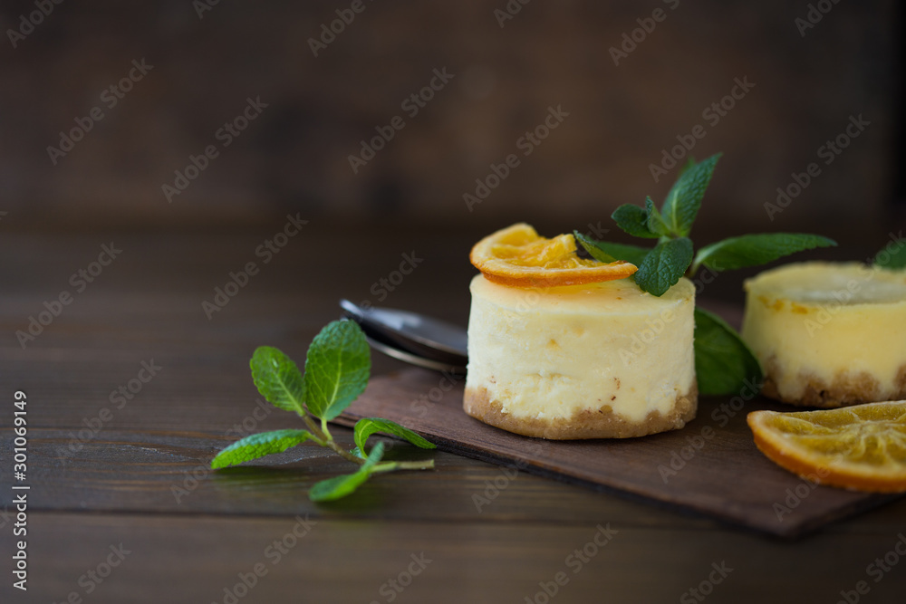 Cheesecake with slices of orange and mint on a wooden background. Top view. Cheesecake with slices of orange and mint on a wooden background. Top view.