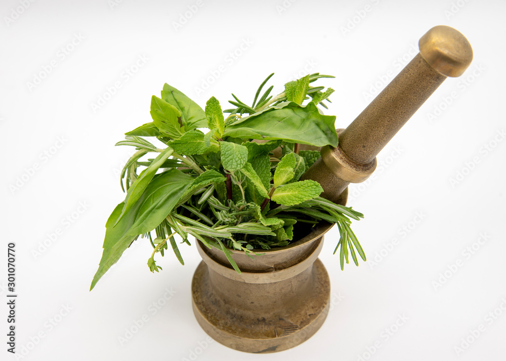 Mortar with pestle and fresh herbs on a light background.