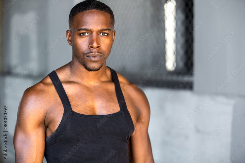 Handsome african american male athlete, strong muscular upper body, serious determined expression in urban setting Handsome african american male athlete, strong muscular upper body, serious determined expression in urban setting