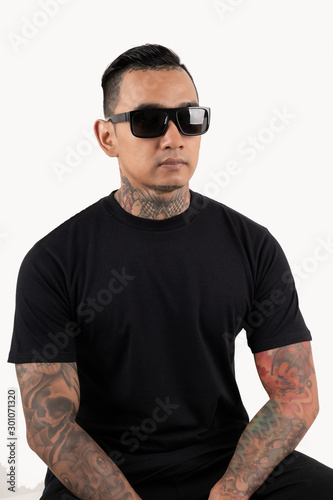 Tattooed man sitting wearing black t-shirt and sunglasses