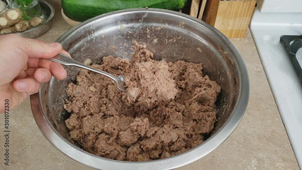 Home cooking - Checking with fork previously cooked and seasoned ground beef in stainless steel bowl making stuffing for croquet or wraps with meat filling. Home cooking - Checking with fork previously cooked and seasoned ground beef in stainless steel bowl making stuffing for croquet or wraps with meat filling.