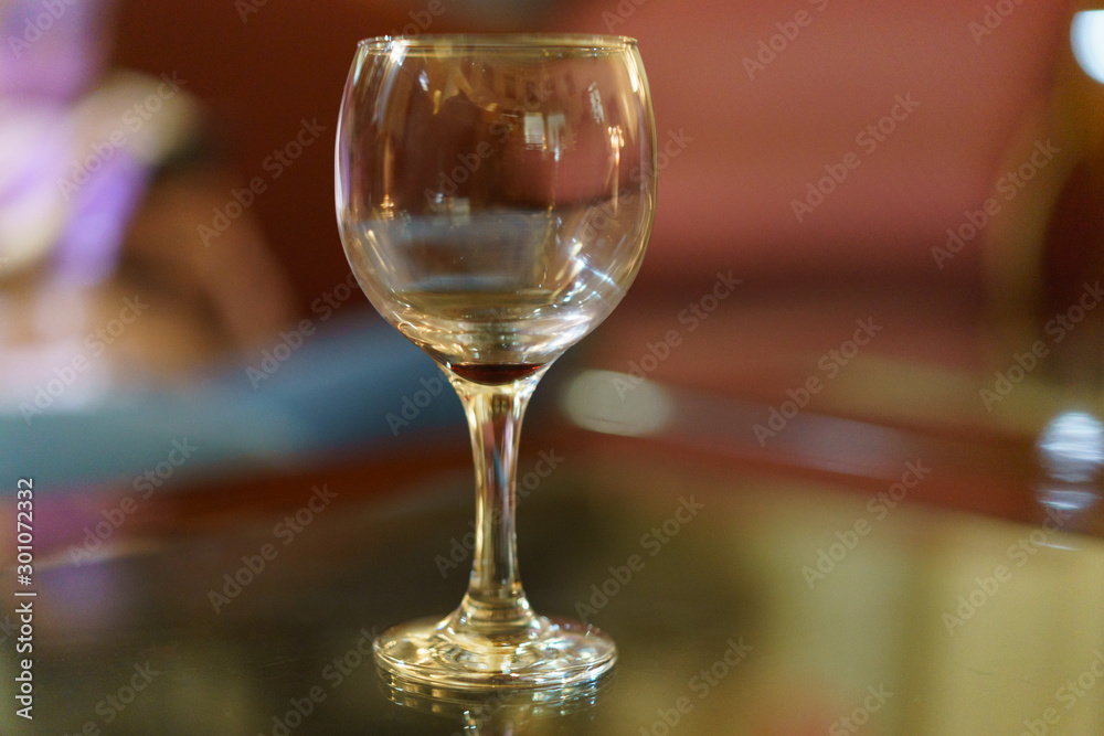 Photography of empty wine glass on the table with defocused background. Indoors image.