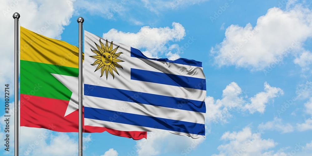 Myanmar and Uruguay flag waving in the wind against white cloudy blue sky together. Diplomacy concept, international relations.