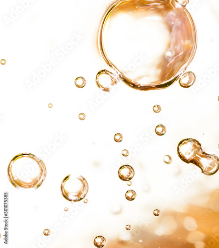 Bubbles of air on the smooth surface of golden water as an abstract background