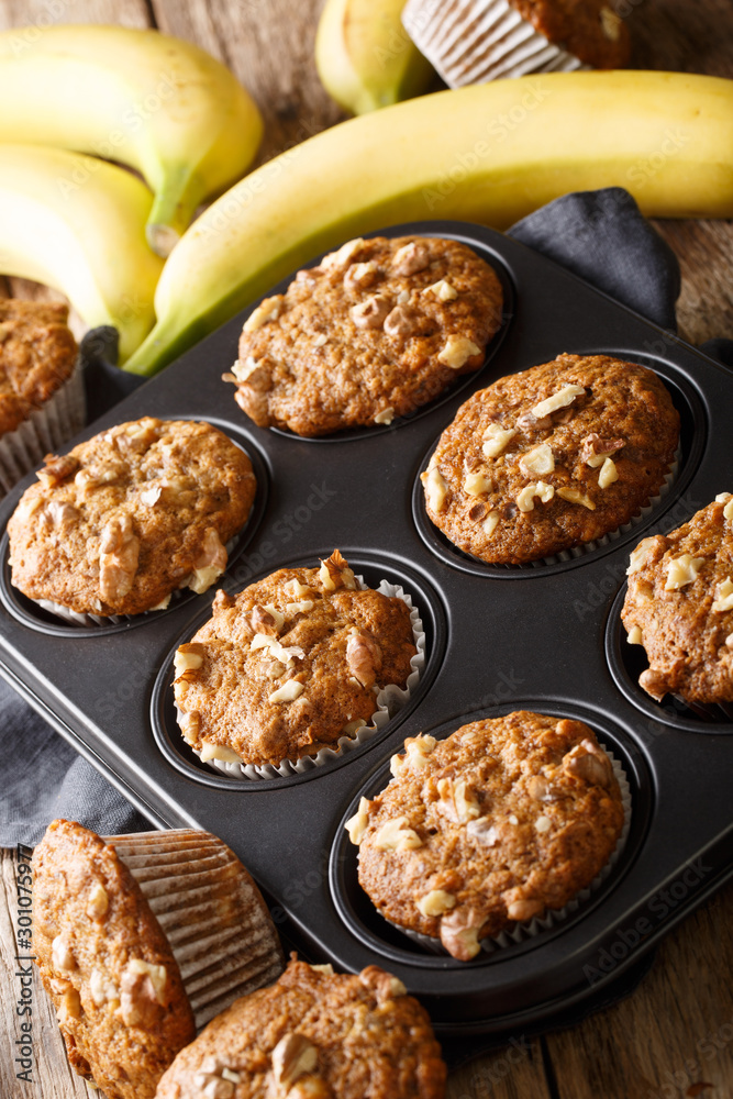 Healthy breakfast banana walnut muffins close-up in a baking dish on the table. vertical Healthy breakfast banana walnut muffins close-up in a baking dish on the table. vertical