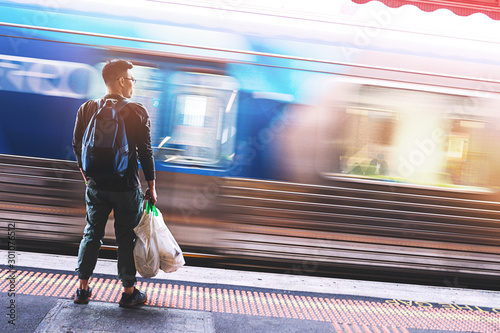 Back of a man waiting for the blurry train under the light leak at station in Melbourne, Australia