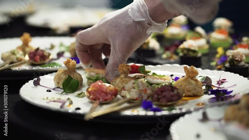 Catering company preparing large numbers of food beautifully decorating it, delicious gourmet meal is being given the finishing touches by the chef in a restaurant.