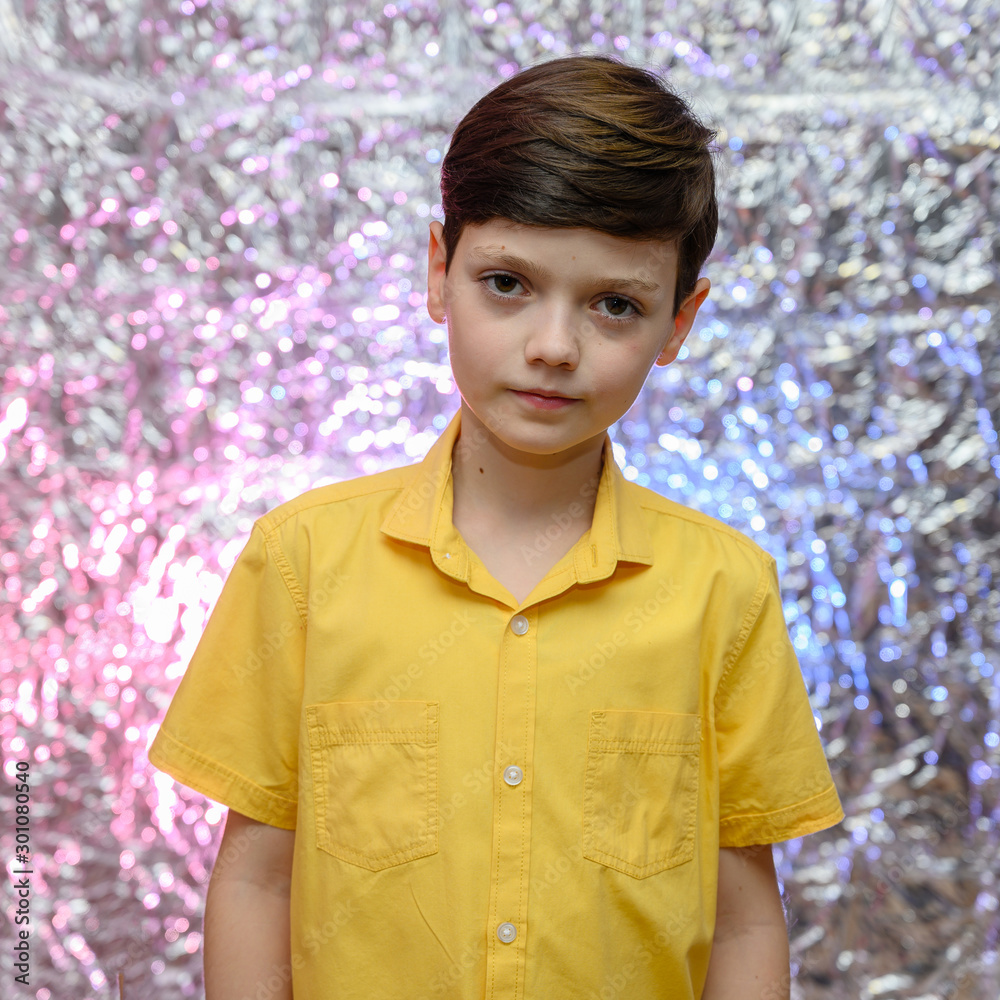 Holiday photo concept for teenager boy. Portrait of a baby boy on a shiny background in a yellow shirt. Stands in front of the camera in different poses with emotions. Holiday photo concept for teenager boy. Portrait of a baby boy on a shiny background in a yellow shirt. Stands in front of the camera in different poses with emotions.