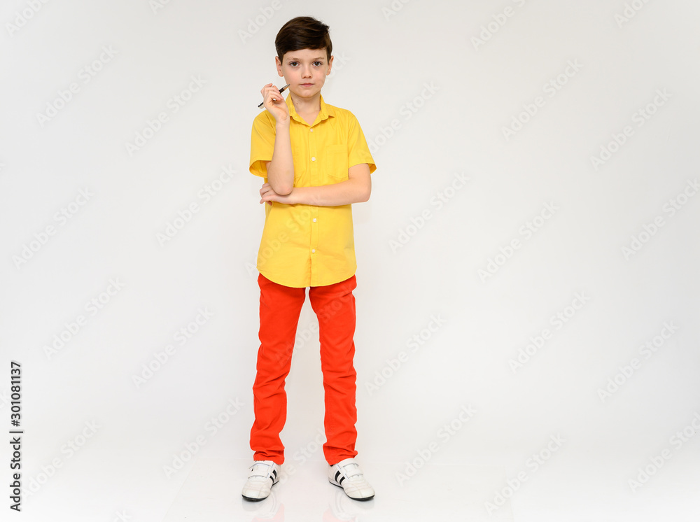 Teenager Schoolboy Boy Concept Shows Emotion. Full-length photo of a child in red pants and a yellow shirt on a white background in studio. Stands in front of the camera in various poses. Teenager Schoolboy Boy Concept Shows Emotion. Full-length photo of a child in red pants and a yellow shirt on a white background in studio. Stands in front of the camera in various poses.