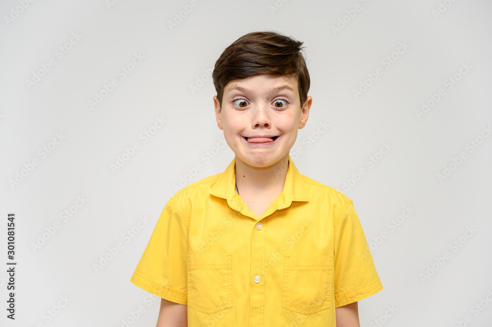 Concept boy teenager shows imitates the behavior of heroes from different movies. Portrait of a child on a white background in a yellow shirt. Standing in front of the camera in poses with emotions. Concept boy teenager shows imitates the behavior of heroes from different movies. Portrait of a child on a white background in a yellow shirt. Standing in front of the camera in poses with emotions.