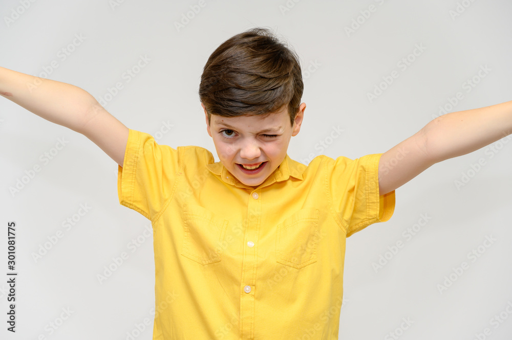 Concept boy teenager shows imitates the behavior of heroes from different movies. Portrait of a child on a white background in a yellow shirt. Standing in front of the camera in poses with emotions. Concept boy teenager shows imitates the behavior of heroes from different movies. Portrait of a child on a white background in a yellow shirt. Standing in front of the camera in poses with emotions.