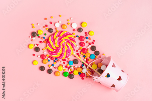 mix colorful chocolate sweets spilled out of bucket with hearts on a pink background Flat lay Top view Place for text Holiday card Happy birthday party, Happy Valentine's day concept