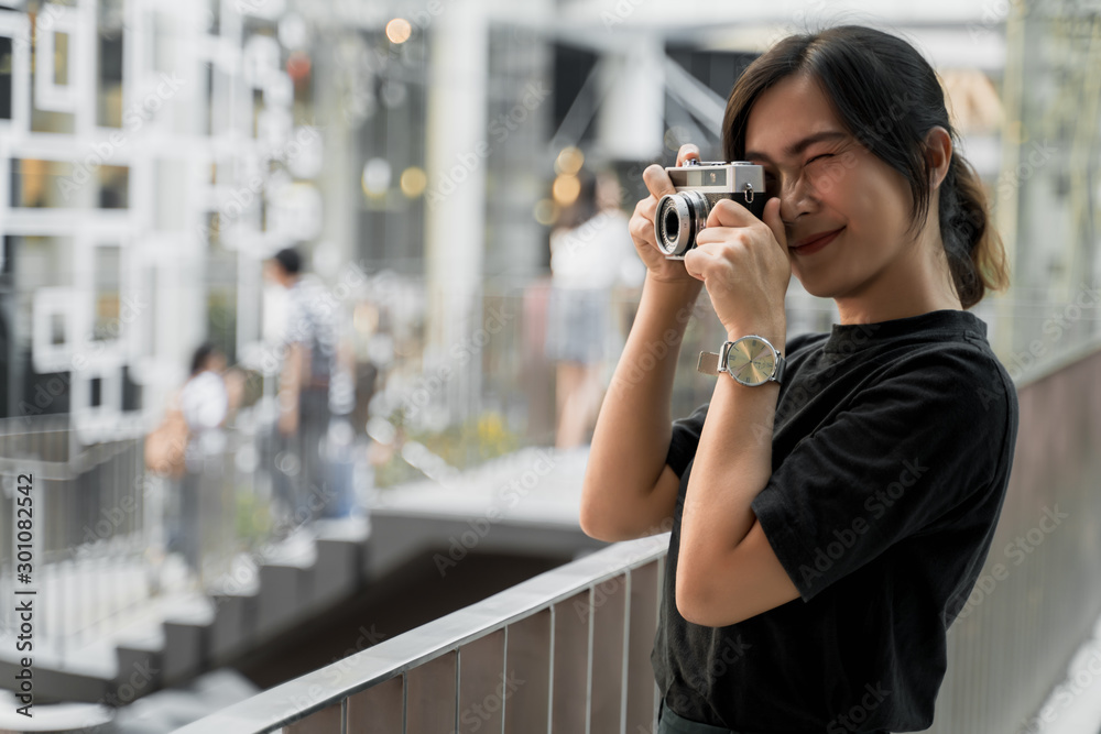 Happy asian woman taking photograph with camera in the city