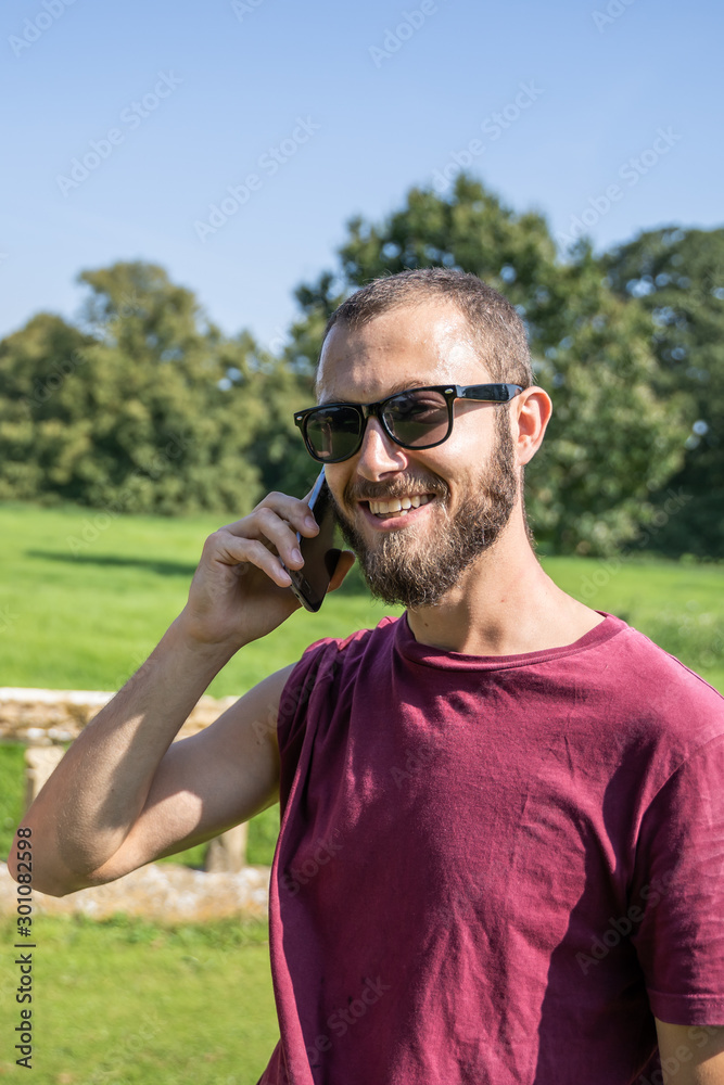 Vertical photo of a guy with sunglasses smiling and talking to the mobile Vertical photo of a guy with sunglasses smiling and talking to the mobile