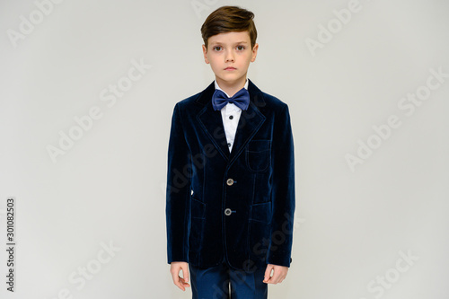 Concept boy teenager shows imitates entertainer behavior on stage. Portrait of a child on a white background in a dark blue concert suit. Standing in front of the camera in poses with emotions.