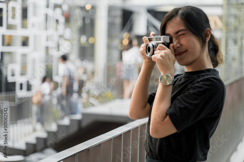 Happy asian woman taking photograph with camera in the city