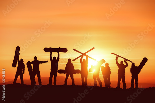 Group of happy silhouettes of skiers and snowboarders
