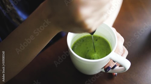 Woman making matcha latte at breakfast close-up