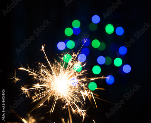 Bengal fire on a black background and blurred bokeh blue lights (new year texture).