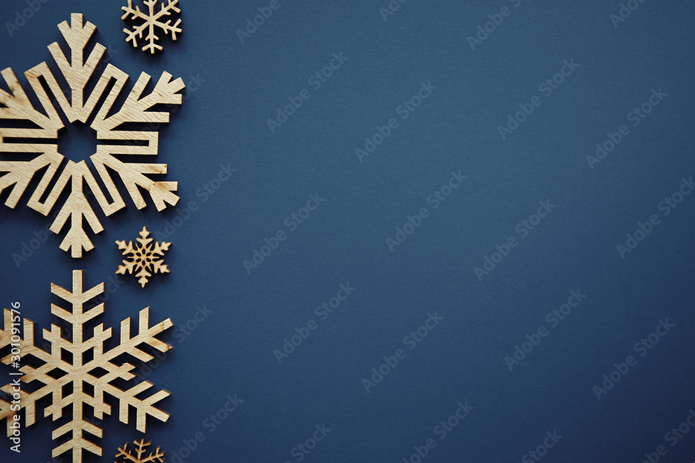 Fototapeta Niebieskie tło Boże Narodzenie z ręcznie robione drewniane płatki śniegu w stylu rustykalnym. Piękny nowy rok tapety z pustej przestrzeni na tekst. Rękodzieło drewniane na szablon plakatu na ferie zimowe. Wystrój świąteczny