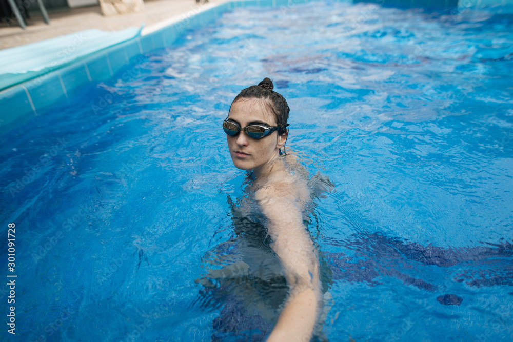 young woman swims in sports glasses in the pool