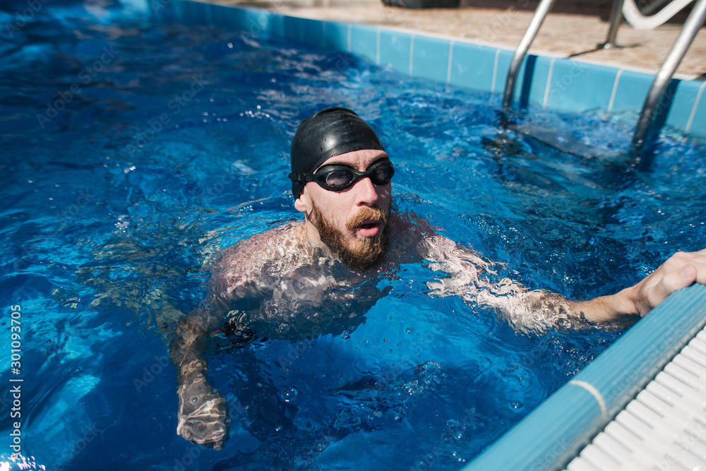 man swims in pool near villa