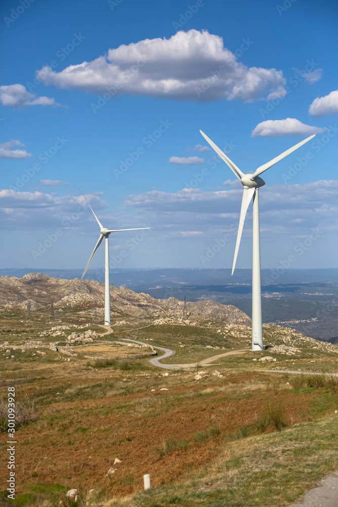 View of a wind turbines on top of mountains, blue sky as background View of a wind turbines on top of mountains, blue sky as background