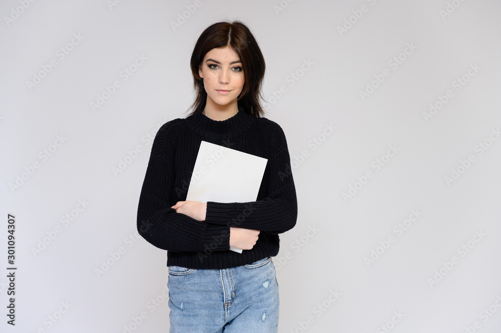Fototapeta premium Portrait of a young pretty girl student with long black hair, on a white background. He stands right in front of the camera, showing his hands in different poses with different emotions.