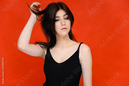 Close-up portrait of a young pretty girl student with long black hair, on a red background. He stands right in front of the camera, showing his hands in different poses with different emotions. photo