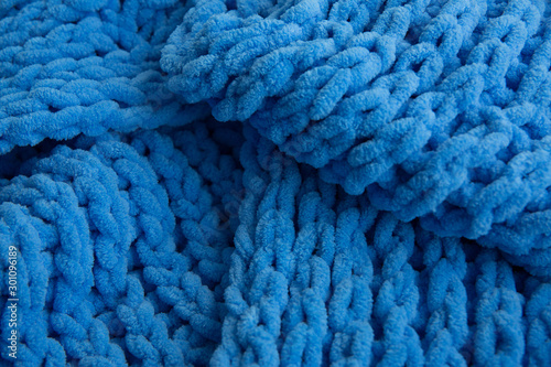 Blue knitted scarf fabric, large knitting, closeup.