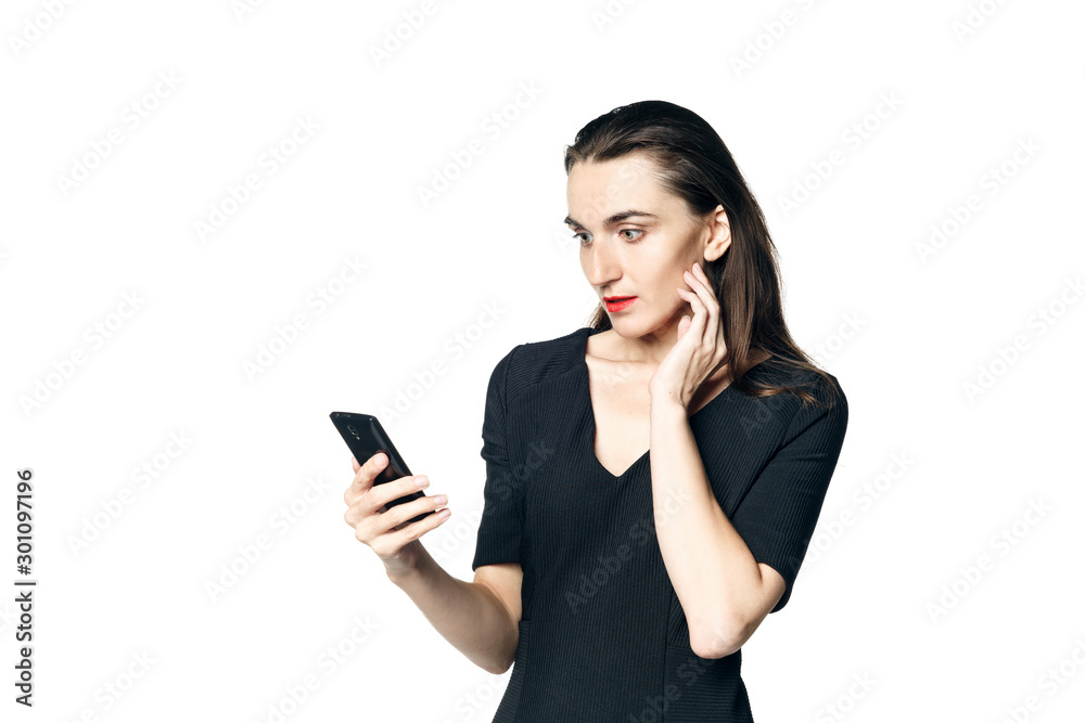 Business woman (fatal woman) in a black dress with red lipstick looks at her phone, isolated on a white background. Business woman (fatal woman) in a black dress with red lipstick looks at her phone, isolated on a white background.