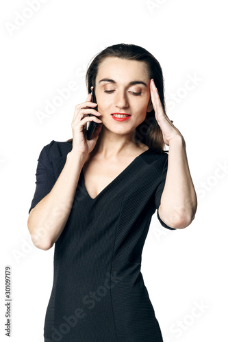 Business woman (fatal woman) in a black dress with red lipstick talking on the phone, isolated on a white background.