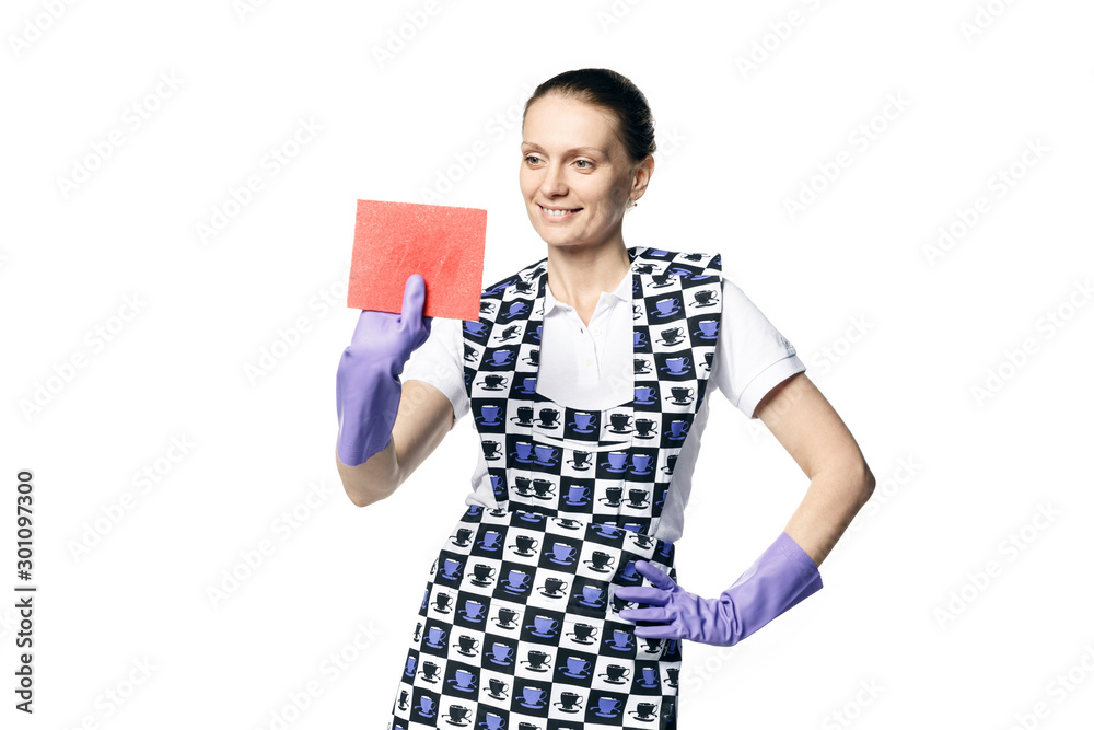 A beautiful young woman in the uniform of a maid holds a rag for washing windows and looks at them in surprise. Isolated on a white background. A beautiful young woman in the uniform of a maid holds a rag for washing windows and looks at them in surprise. Isolated on a white background.