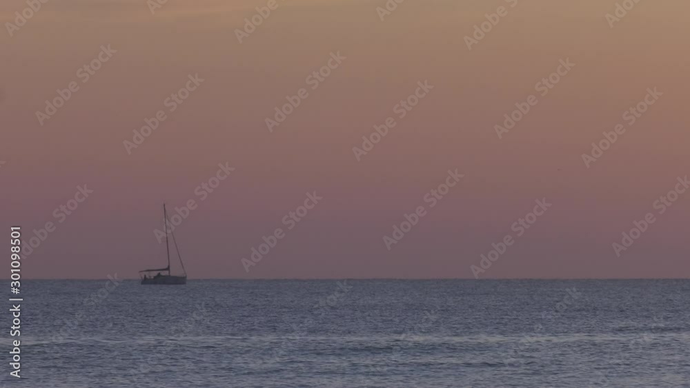 Small Sailing Yacht At Dawn Heading Out To Sea, Sails Furled Small Sailing Yacht At Dawn Heading Out To Sea, Sails Furled