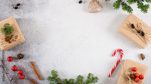 Christmas, New Year banner. Presents in craft paper decorated with natural matereals, candy cane, fir branches on concrete gray background. Flat lay, top view, copy space