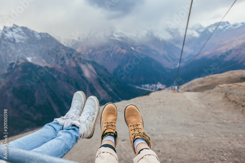 Friends sitting in cable chair and looking at mountains