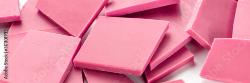 A close-up panorama of ruby chocolate slices, broken on a white background photo