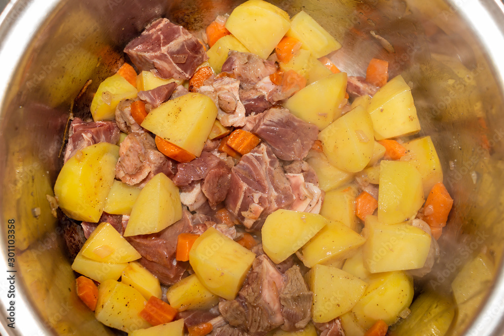 View of the inside of a pot cooking veal with potatoes and carrots View of the inside of a pot cooking veal with potatoes and carrots