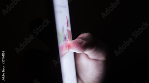 Hand of a dark skined girl scrolling through her phone in the dark photo