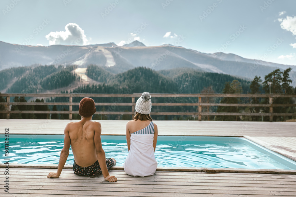 Two people spending vacation in swimming pool with mountain landscape - obrazy, fototapety, plakaty 