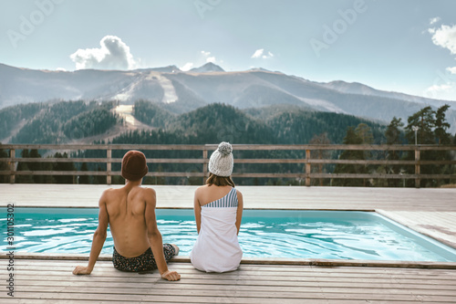 Two people spending vacation in swimming pool with mountain landscape
