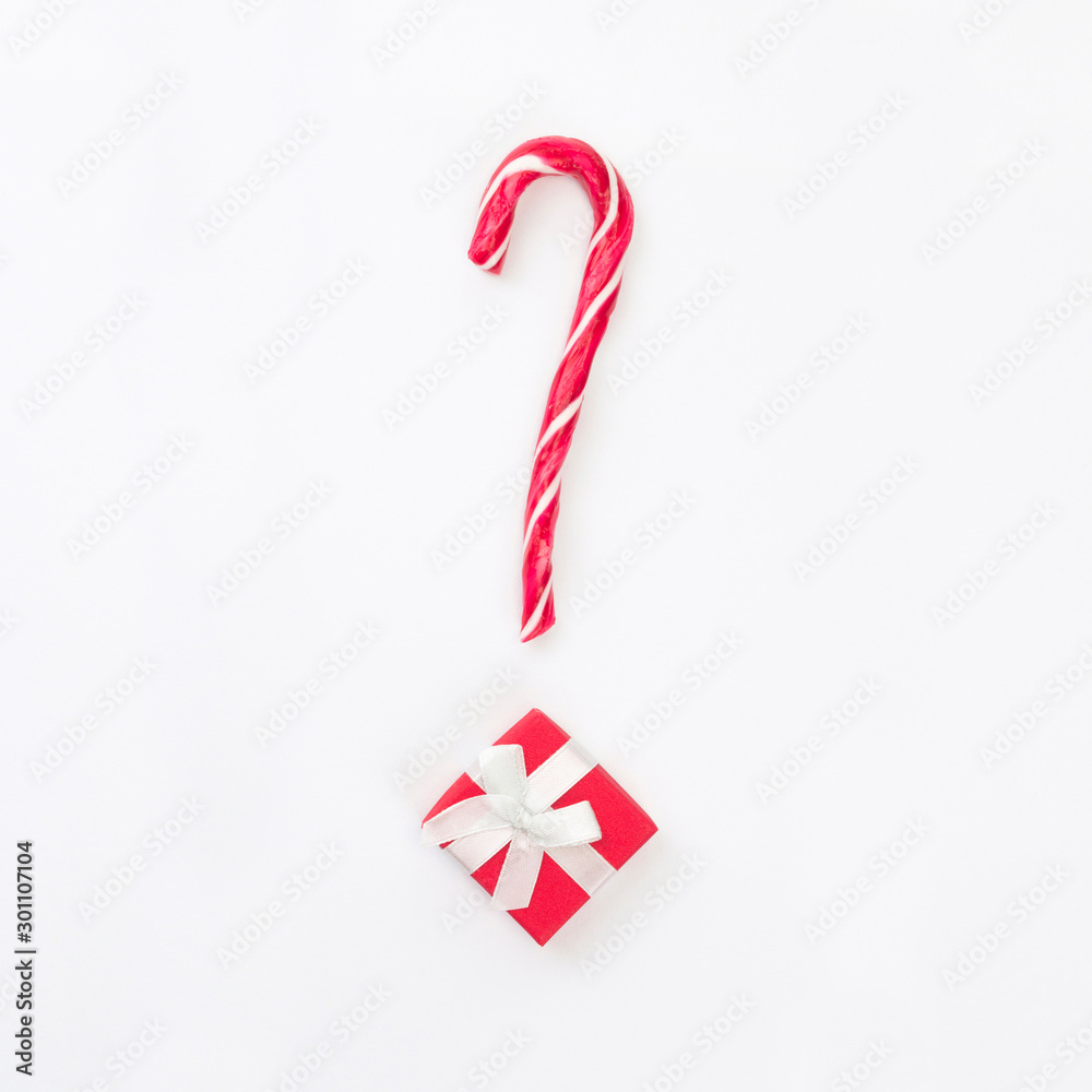 Question mark from Christmas present with candy cane on white background. Gift choice concept. Top view, flat lay, copy space, square format Question mark from Christmas present with candy cane on white background. Gift choice concept. Top view, flat lay, copy space, square format