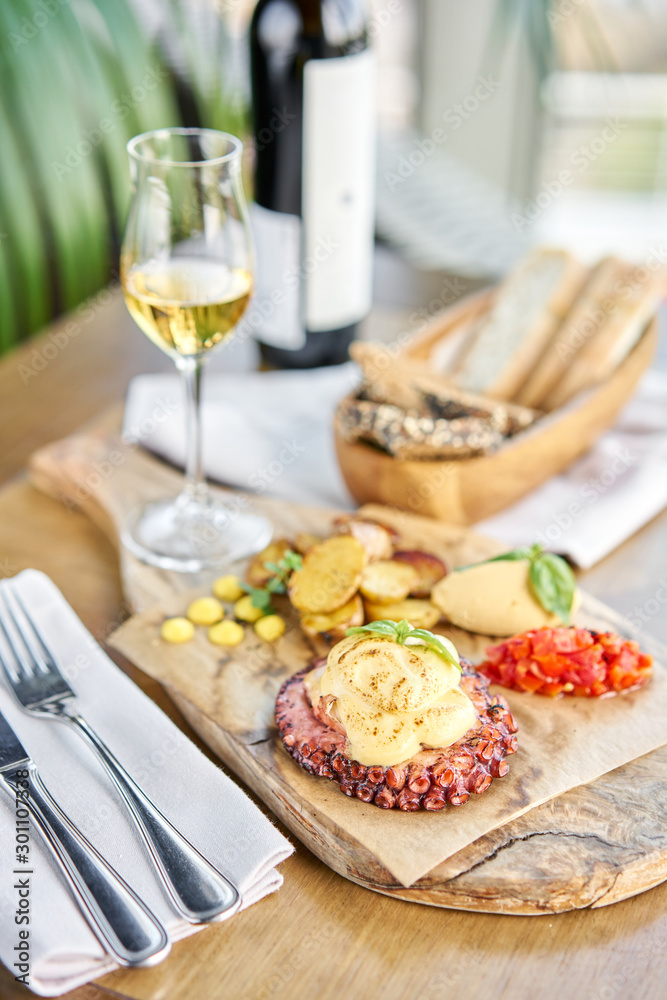 Roasted octopus BBQ and Baked potato with a glass of Grapa. Wooden plate. Restaurant menu Roasted octopus BBQ and Baked potato with a glass of Grapa. Wooden plate. Restaurant menu