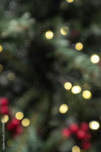 Christmas season background wallpaper texture, blurred out of focus Christmas pine tree decoration red berries and fairy lights